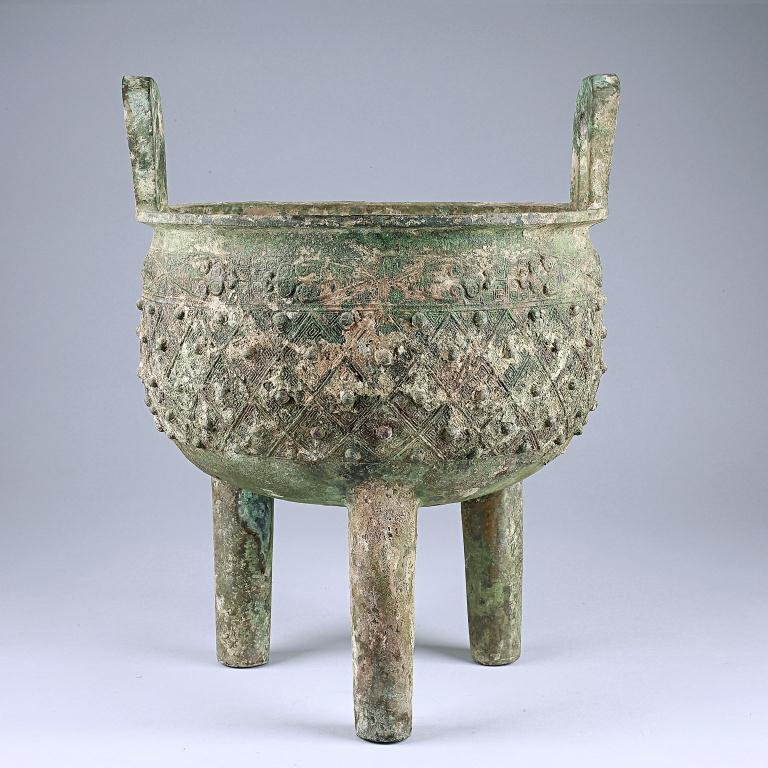 ANTIQUE CHINESE BRONZE TRIPOD INCENSE BURNER: Of globular form standing on tubular legs cast with taotie masks and raised flanges, the flat everted rim set with two upright loop handles and the body finely cast in low relief with repeated diamond