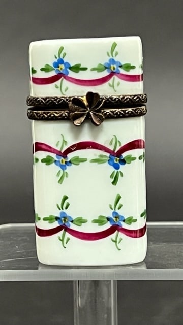 SMALL PORCELAIN HINGED PILL BOX: With a white ground painted with blue flowers, the opening has a design of a double rope and flower clasp
