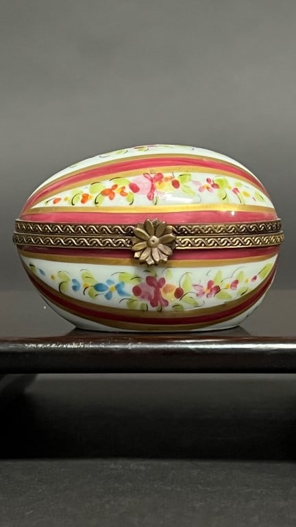 SMALL PORCELAIN EGG-SHAPED PILL BOX: Daintily designed with flowers and bands in pastel colors of yellow and peach, flower clasp opens the egg horizontally.