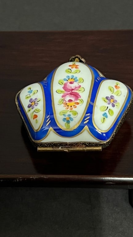 SMALL PORCELAIN PILL BOX: In the shape of a crown, painted with flowers on white ground against blue cartouche. With a gilded flower clasp.