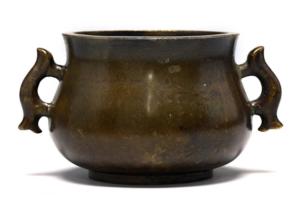 CHINESE BRONZE CENSER MARK STAMPED ON BASE: The body of compressed baluster shape rising from a short tapering foot, set at the waisted neck with a pair of twin handles, the base cast with a six-character mark. Diameter: 4 1/2 in.(11.5cm) x H: 