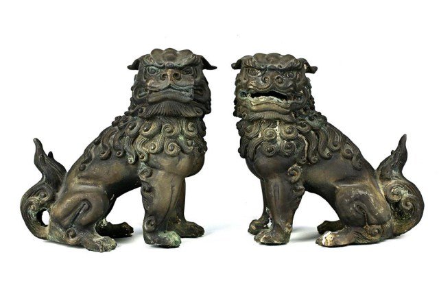 PAIR OF CHINESE BRONZE FIGURES OF FOO DOGS: Finely molded ferocious foo dogs in recumbent position, the heads turned to its sides, with the mouth slightly opened and while the other closed, with detailed curling mane falling to the back. Mildly