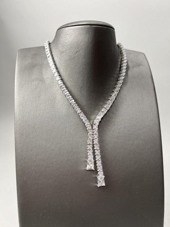 FINE TENNIS NECKLACE W CONJOINED CENTRAL TASSELS: brilliant stones set in white gold plating.
