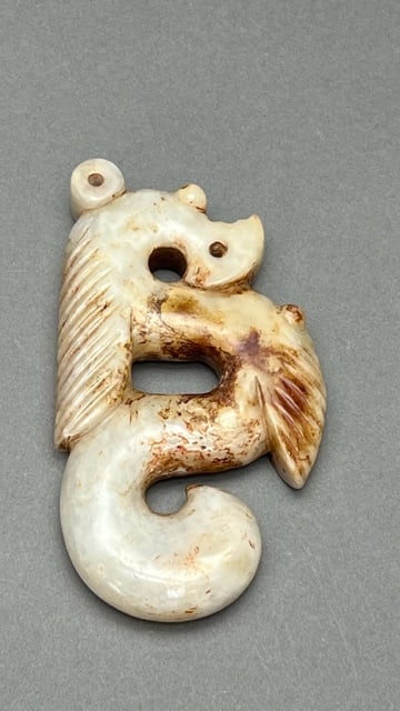 CHINESE CARVED WHITE AND BROWN JADE PENDANT: In mottled white and brown colors; carved as a mystic creature with wings.