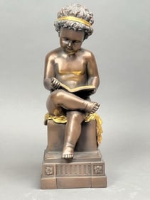 A BRONZE FIGURE OF A READING CHERUB