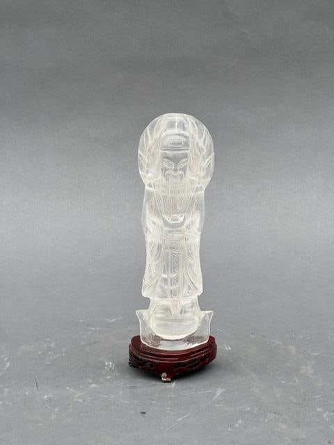 CHINESE CRYSTAL FIGURE OF A MONEY GOD: Carved as a haloed money god, dressing in a robe. With a wooden stand. H: 9 in.
