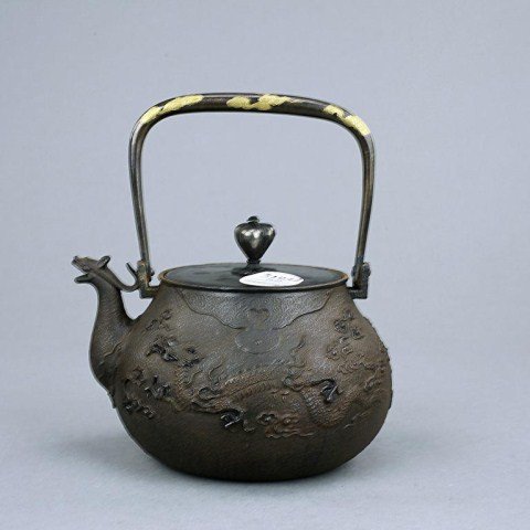 JAPANESE GOLD IN-LAID ZOUROKU BRONZE TEAPOT: Of a slightly compressed bulbous body, flanked by a curved dragon spout and a swing strap handle with gilded scrolling cloud design, the body decorated with two long scaly dragons amidst clouds; the f