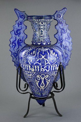 ISLAMIC BLUE AND WHITE JAR ON A TRIPOD METAL BASE: With painting on peacocks on one side, framed by kufi writing in the middle of the jar. H: 25 1/4 in.(64cm)