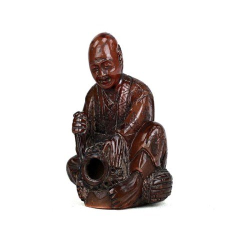 CARVED HORN NETSUKE FIGURE OF A MAN: From the Private Collection of Harry Lawrence of Laguna Beach. sitting on a basket. H: 2 in.(5cm)