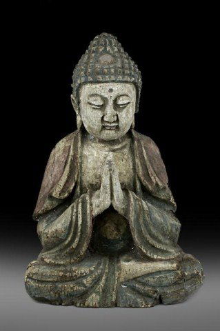 CHINESE POLYCHROMED WOOD FIGURE OF A BODHISATTVA: The Bodhisattva seated in dhyanasana, the hair curled into tight knots surmounted by an ushnisha, with downcast eyes and flanked by two long lobes, dressed in long billowy robes worn over the shoulder