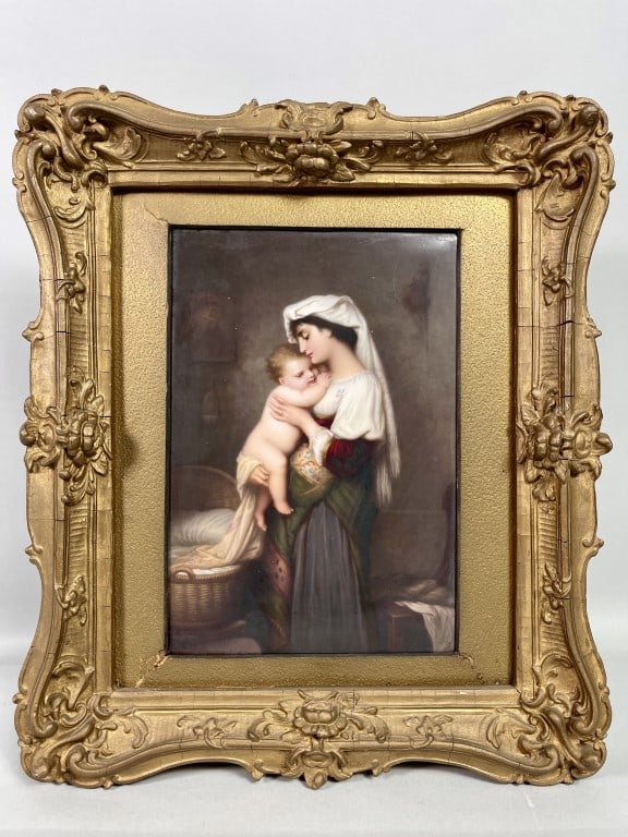 A KPM PLAQUE, OF A MOTHER AND HER CHILD: Dating to late 19th century, encased in an ornate giltwood frame with intricate floral and scroll work detailing. This finely painted porcelain KPM plaque depicts a tender and intimate scene of a moth