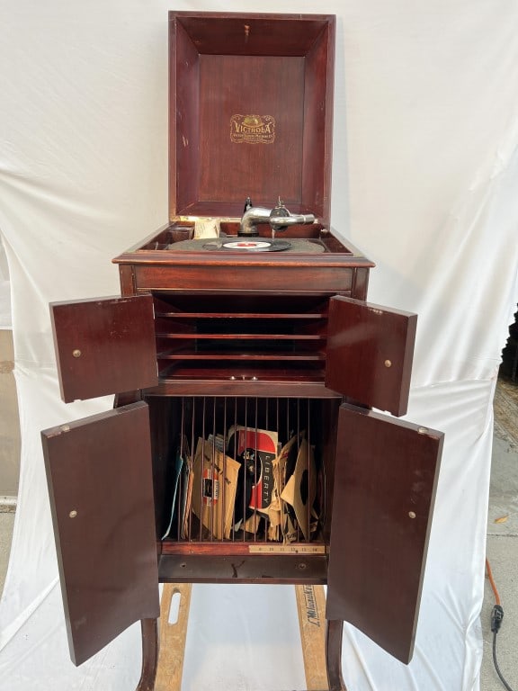 ANTIQUE VICTOR VICTROLA RECORD PLAYER: Manufactured by Victor Talking Machine Co. Raised on four legs, a record player with a standing cabinet. It features a four-door lower record storage cabinets.H: 42 in. W: 16 in. Depth: 20 in.