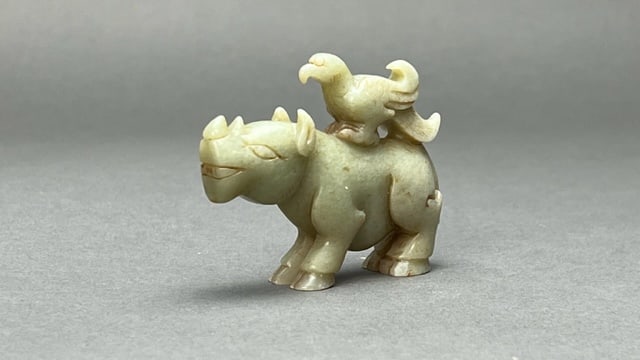 CHINESE CARVED JADE PENDANT OF A RHINO: Carved with a bird standing atop of the back of the rhino. L: 3 1/2 in. H: 2 1/2 in.