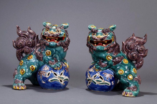 PAIR OF JAPANESE KUTANI PORCELAIN FOO DOGS: decorated with sun vectors throughout, and one paw perched on a reticulated ball. H: 7 2/3 in.(19.5cm)