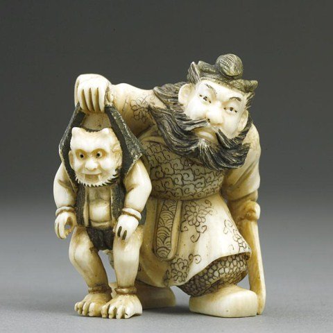 ANTIQUE JAPANESE CARVED IVORY NETSUKE: Of a Samurai holding a sword while he grabs a horned creature by the collar. Signature by the foot. H: 1 5/8 in.