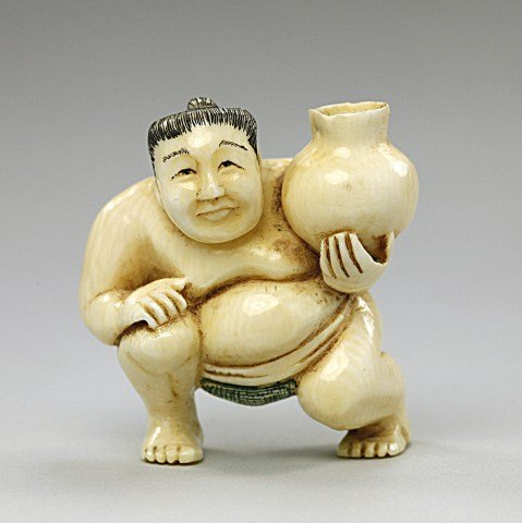 ANTIQUE JAPANESE CARVED IVORY NETSUKE: of a sumo wrestler holding a jar. H: 1 1/2 in.