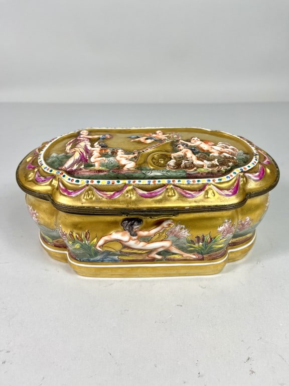LARGE EUROPEAN PORCELAIN JEWELRY BOX: The a gilded background all over, with a hinged cover. Decorated with celestial scenes in relief all around. Marks on the bottom. L: 9 1/2 in. W: 6 in.