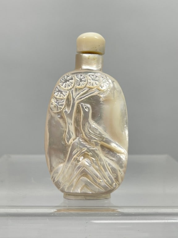 UNUSUAL CHINESE MOTHER-OF-PEARL SNUFF BOTTLE: Carved with a mystic beast on one side of the body; and a scene of a peacock perching on a garden rock on the other side. H: 3 in. W: 1 5/8 in.