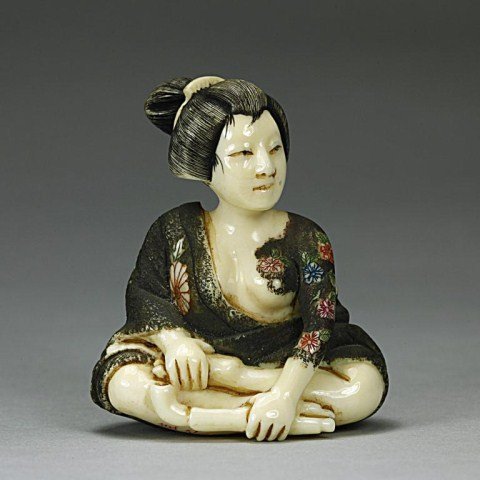 ANTIQUE JAPANESE CARVED NETSUKE: of a polychromed sitting geisha holding a pipe. H: 1 3/4 in.