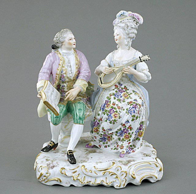 PORCELAIN FIGURAL GROUP OF LOVERS: The lady playing the banjo while the gentleman holds up the music book for her. Blue under-glaze mark on the base. H: 8 5/8 in.