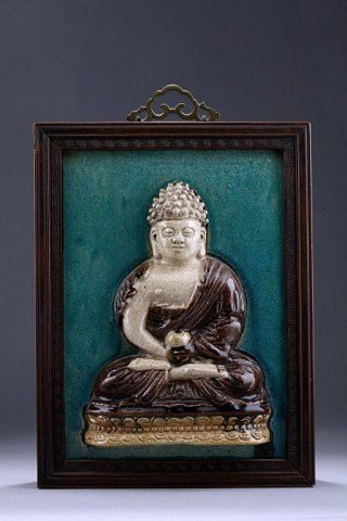 ANTIQUE THAI PORCELAIN TILE PANEL: With the image of Buddha in high relief. He is seated in vajraparyankasana position, the hands clasped in dhyanasana and holds a bowl, he wears a pleated robe, draped over his left shoulder and falls 