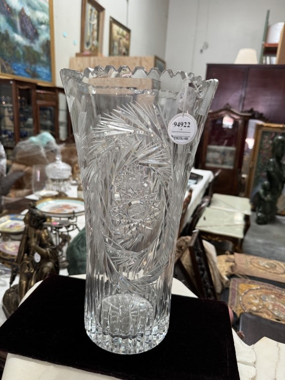 LARGE CONTINENTAL CUT CRYSTAL TRUMPET VASE: The trumpet-shaped body tapers down from a wide, flared rim deeply cut with a bold saw-tooth edge. The exterior is intricately decorated with deep-cut geometric reliefs, featuring a repeating motif of