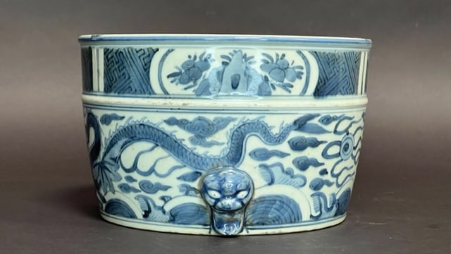 CHINESE BLUE AND WHITE BRUSH POT: Depicting of a dragon chasing pearl amidst clouds and flames. With beast face appliques on the bottom of the pot. H: 5 1/2 in. D: 8 3/4 in.