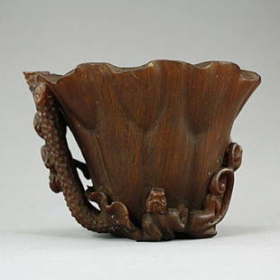 CHINESE CARVED HORN LIKE CUP: A rhinoceros horn-like libation cup carved as the shape of a blossoming flower with chilong on the exterior. H: 3 5/8 in.