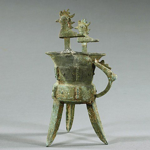 CHINESE BRONZE LIBATION CUP: Chinese Bronze Shang Dynasty Style libation cup supported by three legs. H: 10 1/4 in.