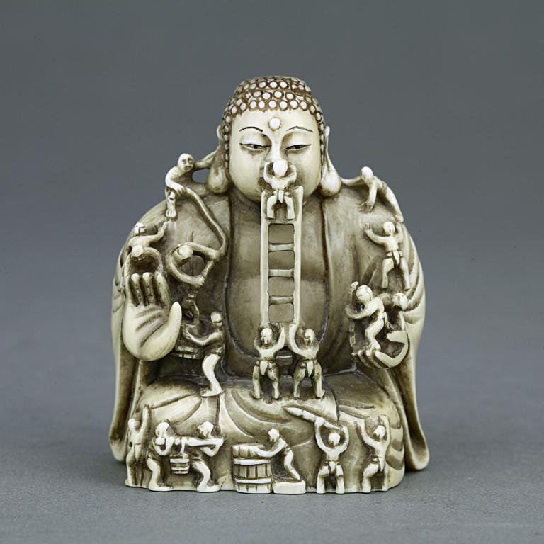 ANTIQUE JAPANESE CARVED IVORY NETSUKE: From the Private collection of Mr. Paul Siegal. An amazing detail of men sculpting a giant Buddha. H: 2 in.(5cm)