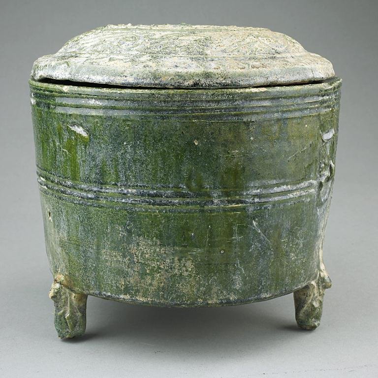 CHINESE HAN DYNASTY GREEN GLAZED TRIPOD BOWL: With masks on the sides in low relief as handles, and incised rings to the exterior of the body. H: 7 1/2 in.