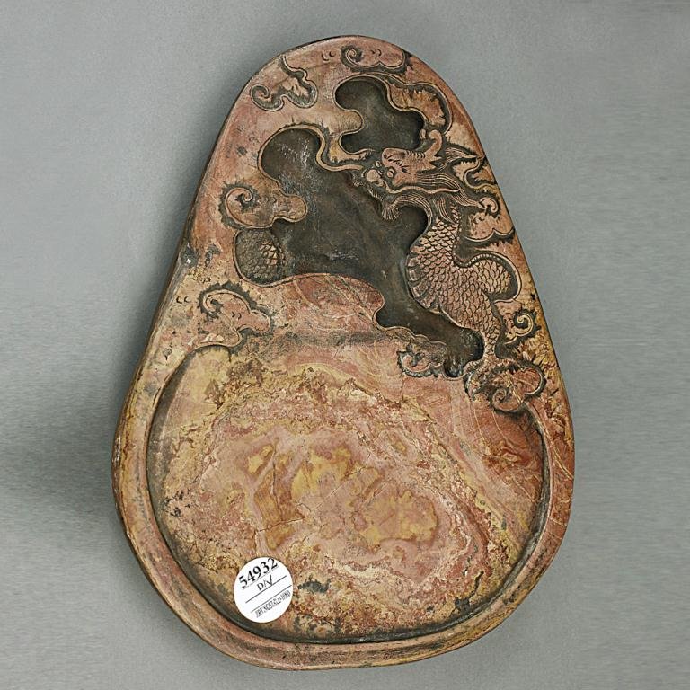 CHINESE CARVED STONE INKSTAND: In a flattened pear shape, decorated with carved dragons on the side, inscribed on the bottom, made by Wang Su. L: 10 3/8 in. x W: 8 3/8 in.