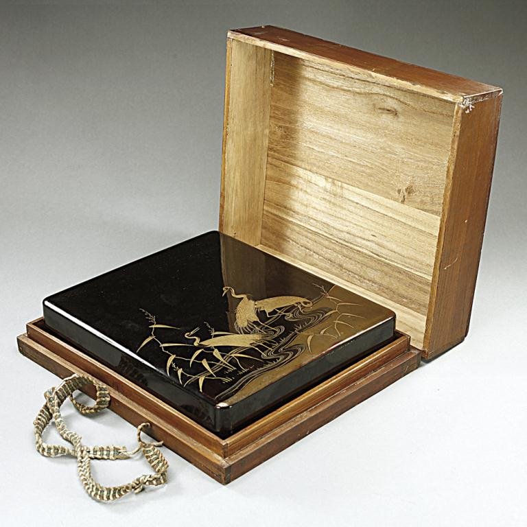 MEIJI PERIOD JAPANESE LACQUERED WRITER'S BOX: Of square with rounded edges designed to the exterior with three cranes lounging in a pond setting, the interior fitted with a rounded rectangular inkstone and silver water dropper. L: 8 1/2 in. x W: 