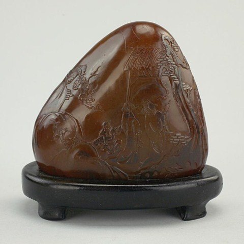 CHINESE CARVED SOAPSTONE ON WOODEN STAND: With carving of Lohans around the mountain. H: 3 7/8 in.