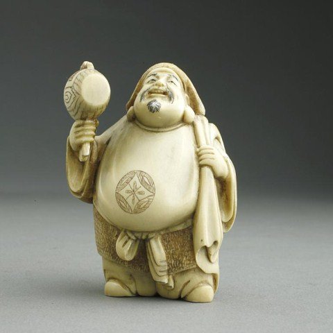 ANTIQUE JAPANESE CARVED IVORY NETSUKE FIGURE: of Daikoku holding his golden mallet and his bag. H: 2 in.