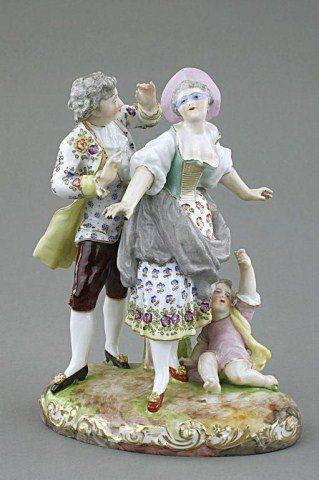PORCELAIN FIGURAL GROUP OF LOVERS AND A CHILD: Featuring a vivid moment between a young couple/lovers playing hide and seek with a boy lying next to the lady. A decorative floral pattern is delicately applied. Blue under-glaze crossed mark on the