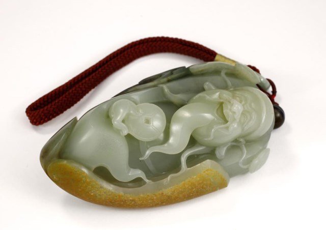 CHINESE CARVED RIVER JADE PENDANT OF A MONEY GOD: With long beard and wearing a hat. The right hand is holding a big coin. H: 4 1/2 in.