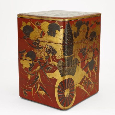 JAPANESE STACKING LACQUER BENTO BOX: From the private estate of Mr. Joe Burton. With four compartments. Black and gold design of overflowing baskets of flowers on a wagon. On a red background. H: 11 1/2 in. x L: 9 in. x W: 8 1/4 in.
