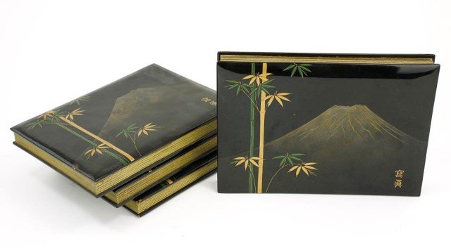 JAPANESE SET OF 4 LACQUER FOLDING WRITING BOOKS: From the private estate of Mr. Joe Burton. Each has black lacquer front and back covers designed with green and gold bamboo stalks in front of Mt. Fuji, and folding cardboard for ink writing. Two char