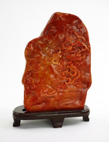 CHINESE SOAPSTONE BOULDER WITH DESIGN OF DRAGONS: Chasing flaming pearls amidst the sky. The boulder stands upon a wooden stand. H: 9 3/4 in.