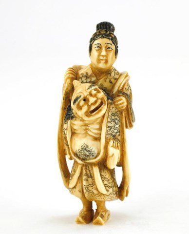 ANTIQUE JAPANESE CARVED IVORY FIGURAL NETSUKE: Of a one-horned man carrying a woman wearing a long scarf on his back. Designs their kimonos are finely carved. H: 2 1/4 in.
