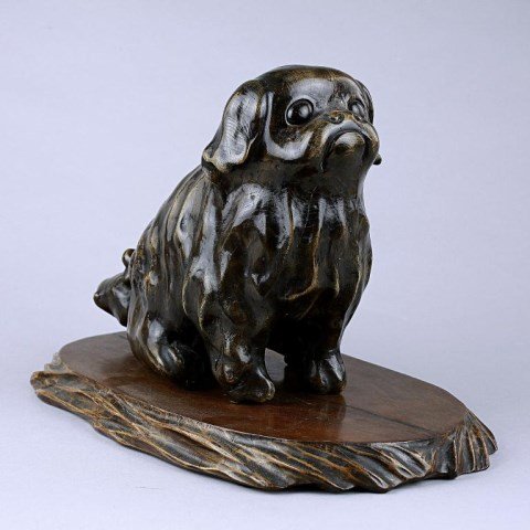 ANTIQUE JAPANESE CARVED WOOD FIGURE OF A PEKINGESE: From the estate of Henry Lawrence of Warren Imports. Realistic rendering, seated upon a flat wooden base. H: 8 3/4 in. (22cm) x L: 12 in. (30cm)