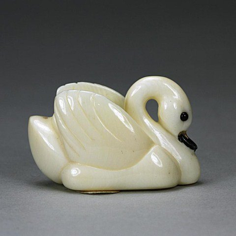 ANTIQUE JAPANESE IVORY NETSUKE OF A SWAN: With inlaid eyes and gilding on the beak. Signature on the bottom to read Masayoshi. H: 7/8 in.