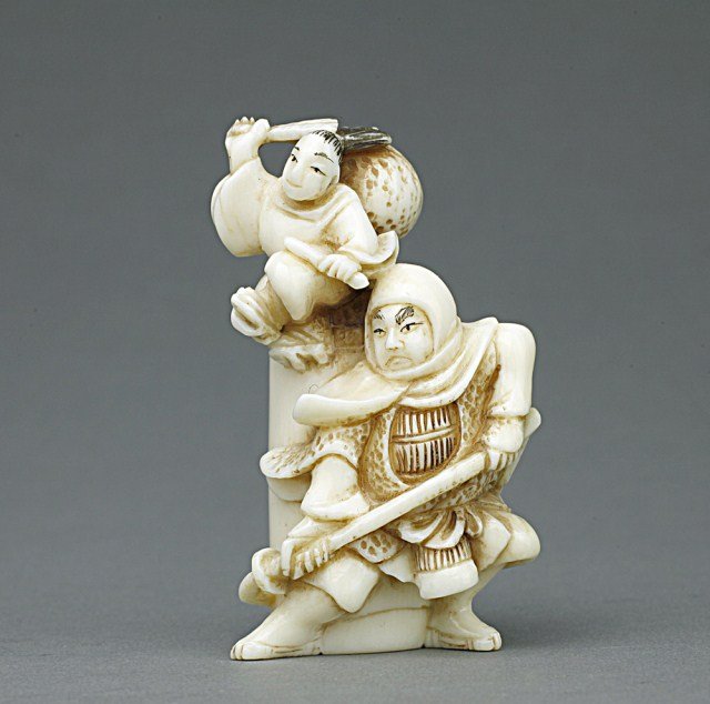 ANTIQUE JAPANESE IVORY NETSUKE OF A WARRIOR: From the private collection of Mr. Paul Seigel. Man wielding a naginata, while a girl holding a fan and stick jumps over him. Four-character signature on the back on mother-of-pearl inlay. H: 2 1/8 in