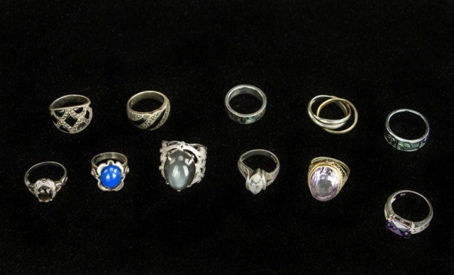 GROUP OF ASSORTED RINGS: Including a grey moonstone ring set on an 18 karat white gold band, with small zirconias inlaid into a scrolling design; and a cut amethyst ring on a double gold band. Eleven rings total.