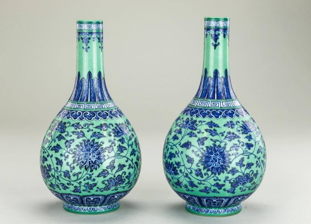 PAIR OF CHINESE BLUE & GREEN BOTTLE NECK VASES: Scrolling lotus designs on the body in underglaze cobalt blue and white, on green ground painted over the glaze; stylized lotus petals rising from around the short foot; leaf design rising up the neck