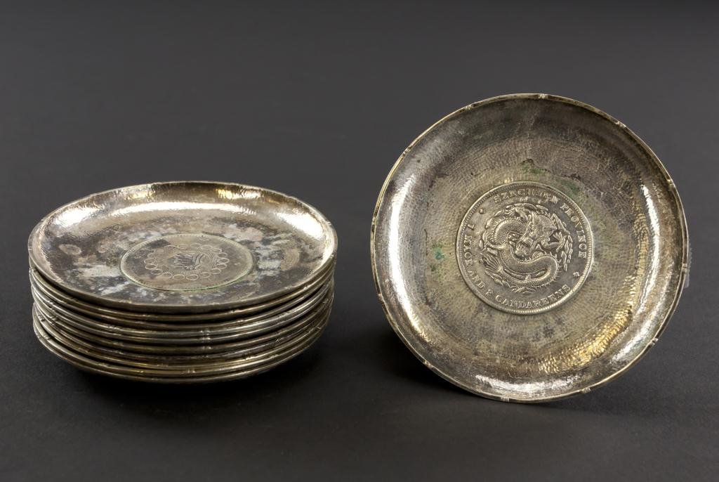 SET OF ELEVEN CHINESE SILVER COASTERS WITH COINS: SET OF ELEVEN CHINESE SILVER COASTERS WITH COINS Each with a unique coin moulded in the center to the interior and exterior. From the Marlin collection of Beverly Hills, CA. Diameter: 3 1/2 in.