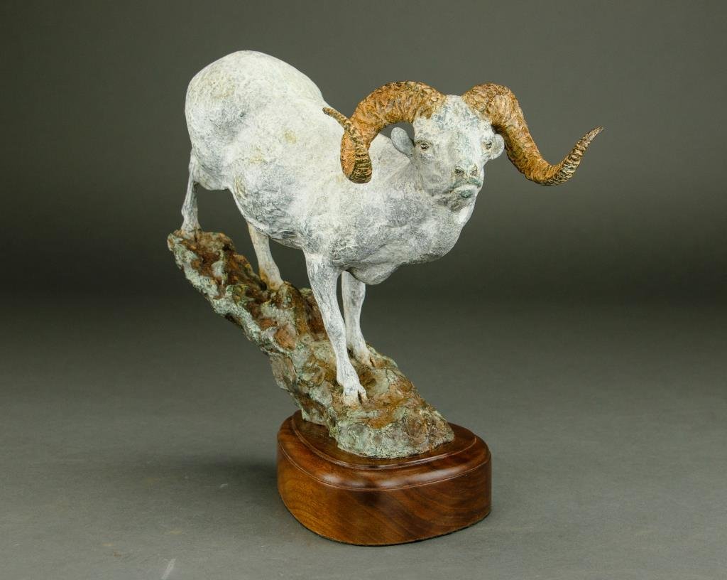 COLD PAINTED BRONZE FIGURE OF A RAM: COLD PAINTED BRONZE FIGURE OF A RAM Standing upon a rock. 1968 and JS inscribed on the bronze rockery, attributing the piece to Jim Stafford. Mounted on a wooden base. H: 11 3/4 in.