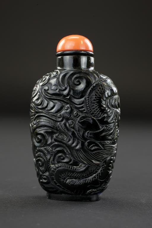 CHINESE CARVED BLACK NEPHRITE JADE SNUFF BOTTLE: CHINESE CARVED BLACK NEPHRITE JADE SNUFF BOTTLE With carved dragon and clouds wrapping around the entire body. On a short foot. Circa 1880-1920. From the Marks Collection. H: 2 5/8 in.
