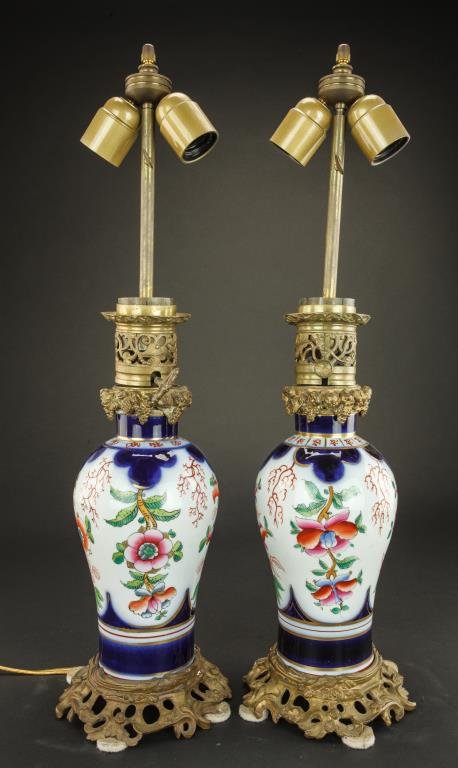 PAIR OF RUSSIAN PORCELAIN LAMPS: Hand painted with multicolor oriental floral motif on the body with blue powder bands and gilt detailing. Mounted upon a cast scrolling designed base and top. H: 9 in.